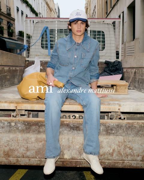 This ad features a man sitting in the back of a truck wearing a denim outfit and a cap, with a tan bag at his side. The