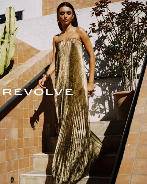 An image ad for Revolve, featuring a woman in a gold dress walking down a staircase.