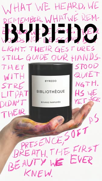 This image ad showcases a Byredo Bibliothèque candle held in a hand with paint smudges on it. The background is white wi