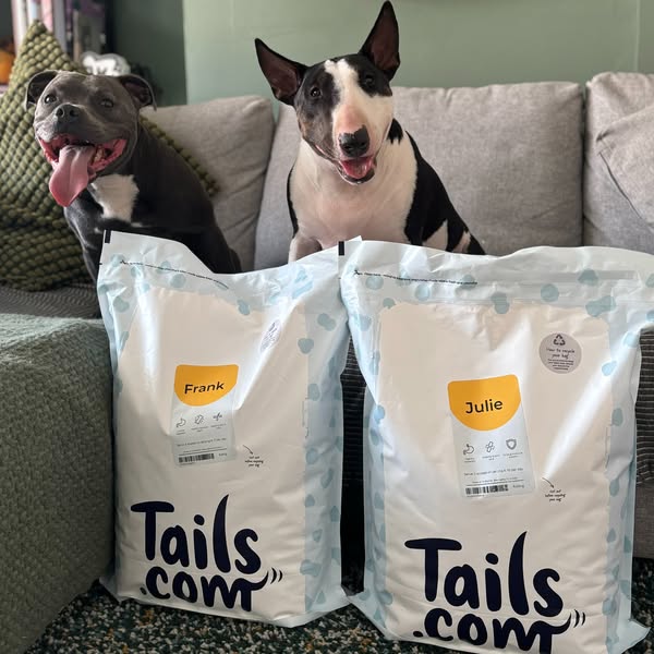 This ad features two dogs sitting behind bags of Tails.com dog food that are personalized with their names. The ad is li