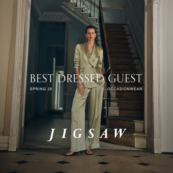The image ad showcases a woman in a satiny light green suit standing in front of a staircase inside a building. The ad s