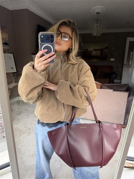 This ad features a woman taking a selfie in the mirror while holding a large tote bag. The ad is designed to showcase th