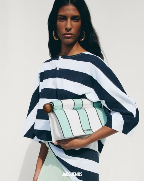 This ad features a still photo of a model wearing a Jacquemus striped shirt and carrying a matching striped handbag.