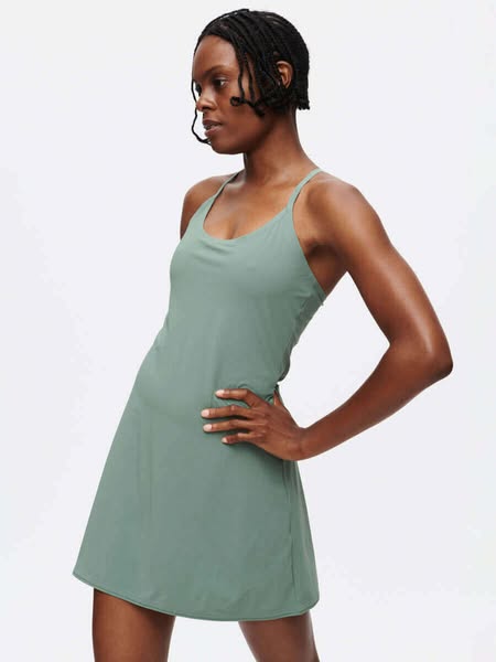 This ad showcases a woman wearing a light green exercise dress against a white background.