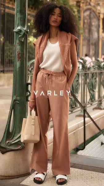 This image ad features a young woman wearing clothing from the brand Varley. She is standing outdoors in what appears to