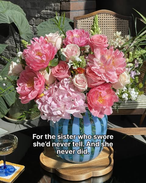 This ad features a vase of pink flowers in front of a brick background. There is a glass of champagne to the side, and i