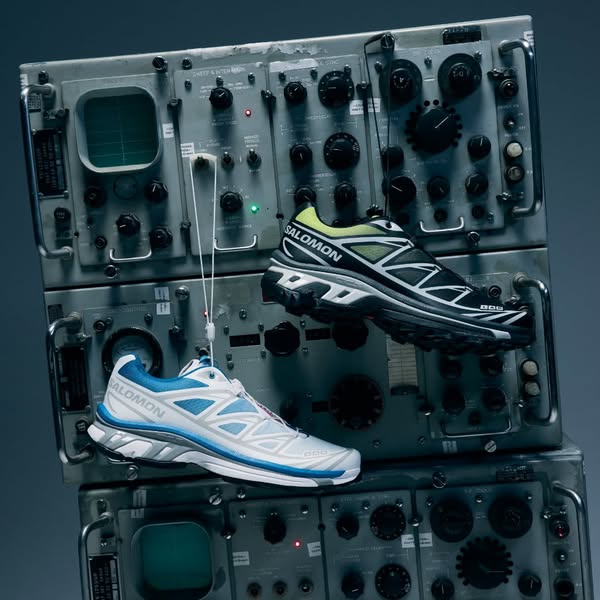 This ad showcases two different Salomon running shoes suspended in front of a gray industrial backdrop. The colors of th