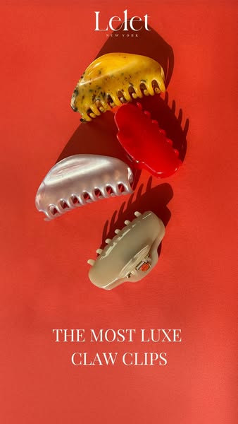 This image ad for Lelet NY features a flatlay of four claw clips in different colors and materials against a coral backg