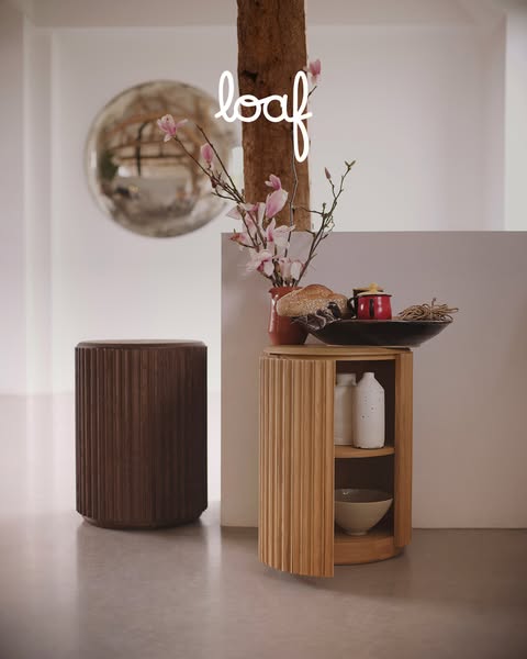 An ad featuring two ridged wooden side tables, one dark and one light, in a staged interior setting. The ad promotes the