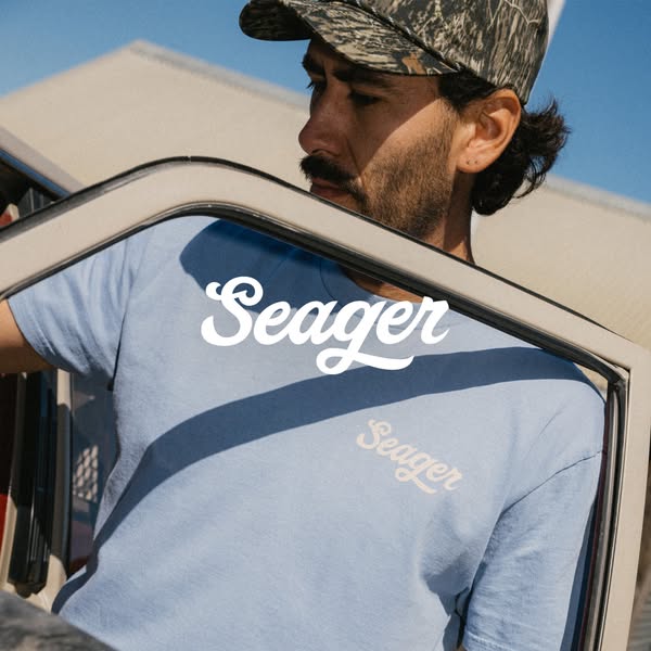 This image ad features a man wearing a blue Seager T-shirt. The ad showcases the brand's T-shirt with the brand logo