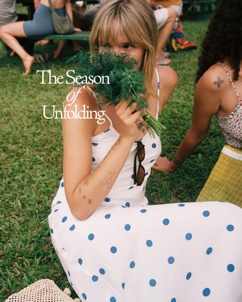This ad features a woman partially concealing her face with a bunch of dill as she sits on the grass in front of a small