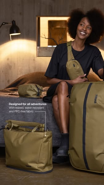 A woman is seen sitting on a bed with several Thule brand bags. The ad showcases the bag's material and says they ar