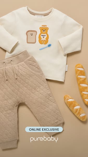This ad showcases baby clothing from Purebaby, featuring a long sleeve shirt with a cute toast and honey bear design pai