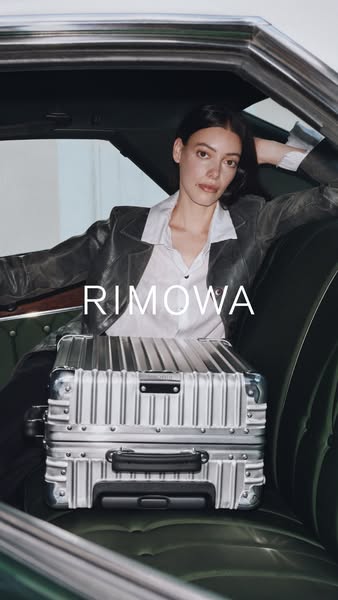 This image ad showcases a RIMOWA suitcase positioned in the backseat of a vintage car, next to a model who is leaning ba
