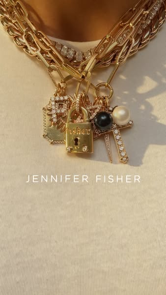 The ad is a close-up shot of several gold necklaces with charms on a white shirt background. The brand name is shown at 