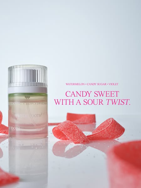 This image ad presents Sweet Tooth fragrance in a brightly lit setting. The bottle is surrounded by red candy strips tha