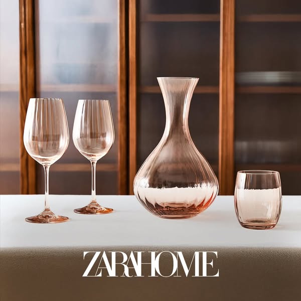 This Zara Home ad showcases a selection of glassware, including wine glasses, a decanter, and a tumbler, set against a s