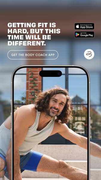 This image ad for The Body Coach app features Joe Wicks stretching and smiling, framed within a phone screen. The ad emp