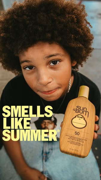 A close up image of a person holding a Sun Bum sunscreen bottle. The headline calls out the scent with the text "SM