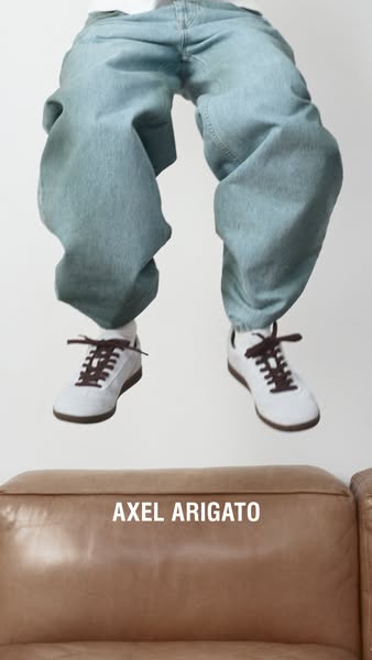 This image promotes footwear by Axel Arigato. The product is featured worn by a person who is floating in the air above 