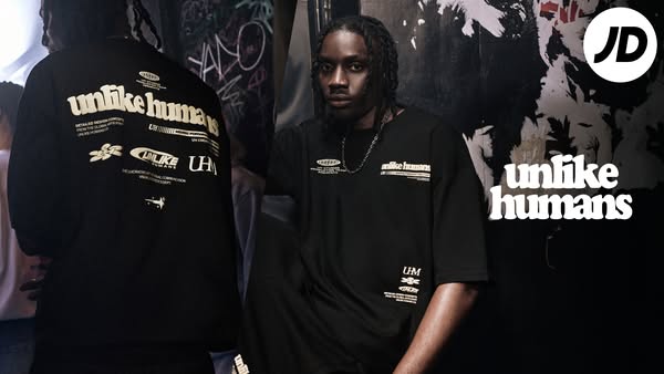 This ad showcases the Unlike Humans brand. It shows a model wearing a black t-shirt with the brand's name and logo. 