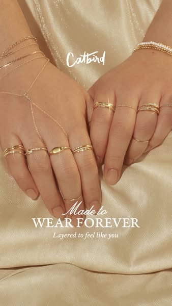 Close up shot of model’s hands that are layered with various gold rings and bracelets from Catbird. Focuses on the abili