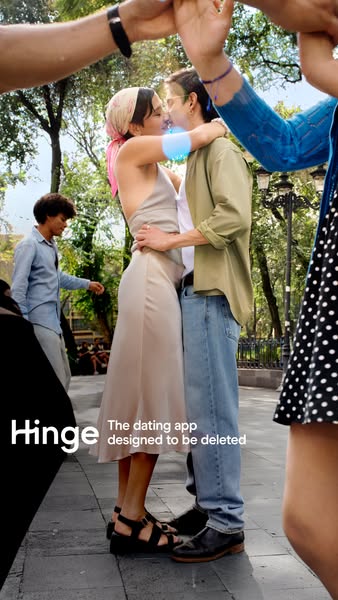This Hinge ad shows a couple kissing in an urban environment, while other people are around them, making a square with t