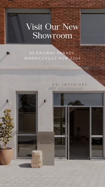 This ad promotes a visit to ABI Interiors' new showroom, showcasing the exterior of the building with its modern des