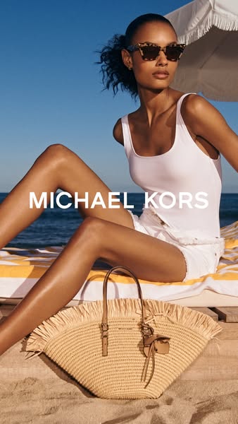 This Michael Kors ad features a model on a beach using a Michael Kors straw tote bag. The ad focuses on the brand name a