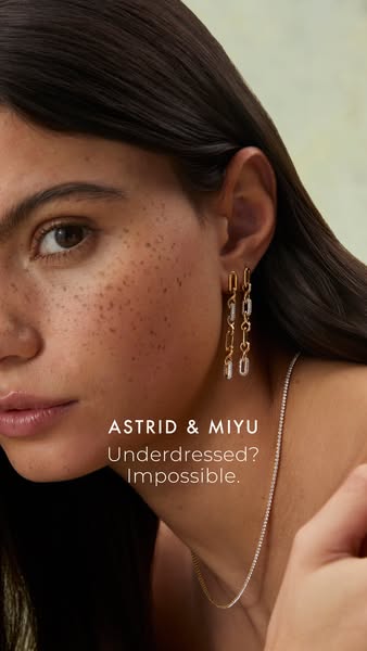 This image ad from Astrid & Miyu features a close-up of a woman wearing their earrings and necklace, paired with the