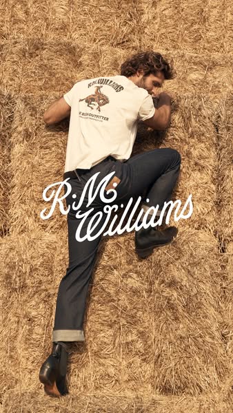 This image features a person laying on hay bales, wearing R.M. Williams brand jeans and boots. The brand name is promine