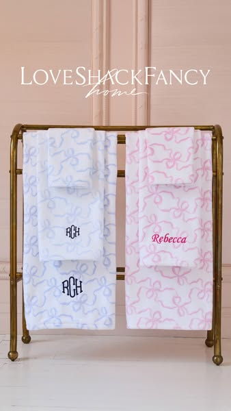 An image ad for LoveShackFancy Home towels. The towels are displayed on a gold colored rack and feature different colore