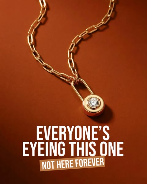 An image promoting a gold chain link necklace featuring a round pendant with a central diamond. The ad uses a warm, invi