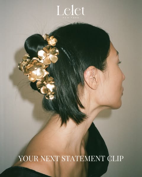 This ad showcases a gold flower hair clip from Lelet NY. The ad features a woman with dark hair wearing the hair clip.