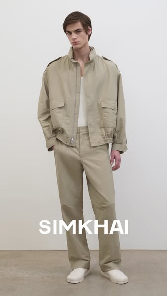 This ad features a full body shot of a male model in a beige outfit by SIMKHAI, consisting of a jacket and pants. The ad