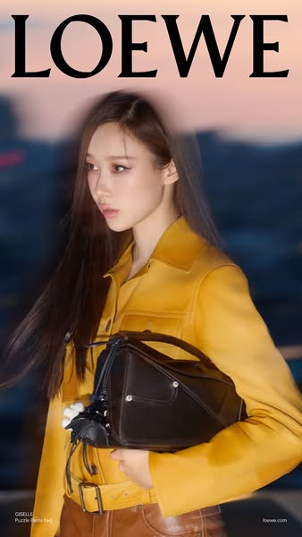 This ad showcases the Loewe brand and the Puzzle hobo bag. The ad features a model holding the bag in front of a blurred