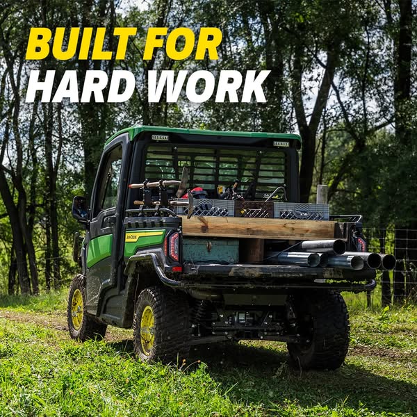 This ad features the back of a John Deere utility vehicle, loaded with equipment, set in an outdoor environment. The hea