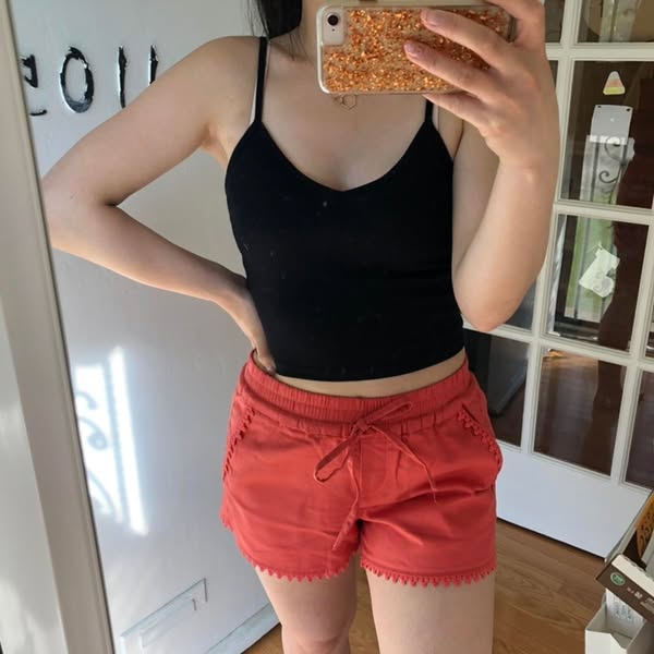 This ad features a woman taking a mirror selfie while wearing a pair of coral shorts. The ad is designed to showcase the