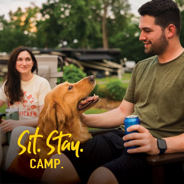 This image ad uses a photograph of a dog being pet by a man, with a woman in the background, to promote the brand. It fe