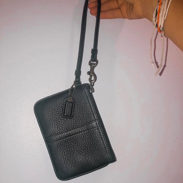This ad showcases a Coach brand wristlet in black. The ad emphasizes the wristlet's versatility and sophistication t