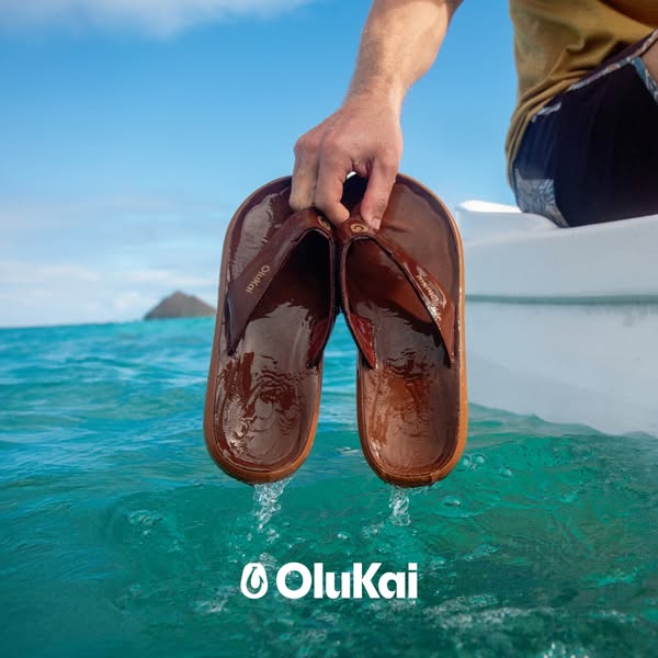 This ad features OluKai brand flip-flops being held over the ocean. The ad is likely targeted towards those who enjoy sp