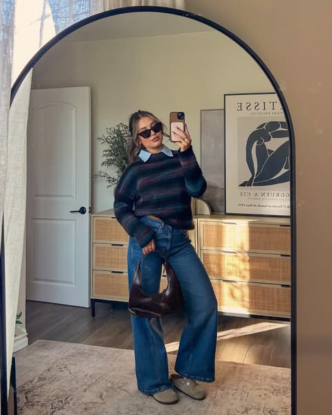 A woman takes a mirror selfie in a casual outfit.