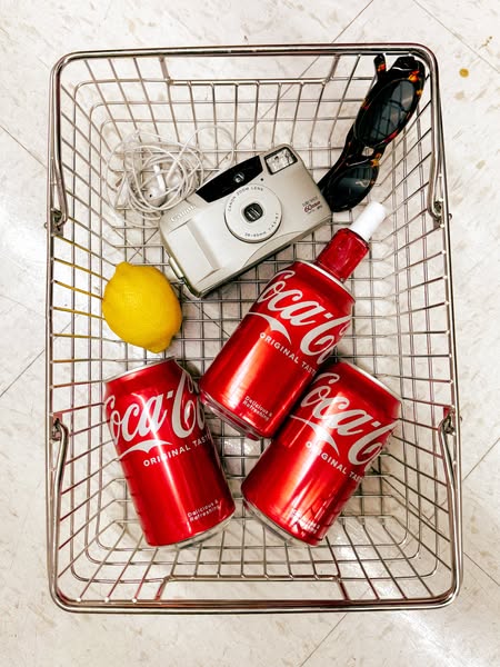 This ad features a product flatlay in a lifestyle setting, with Coca-Cola cans arranged alongside other everyday items i