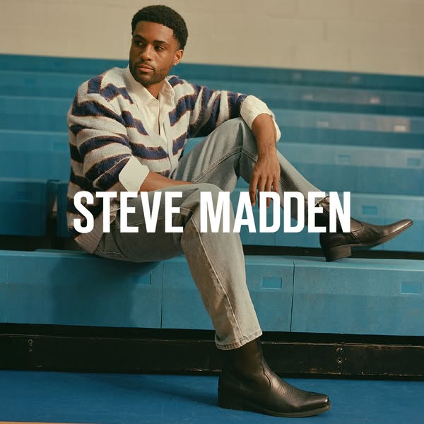 This Steve Madden ad features a man sitting on blue bleachers in jeans, a sweater, and black heeled boots from Steve Mad