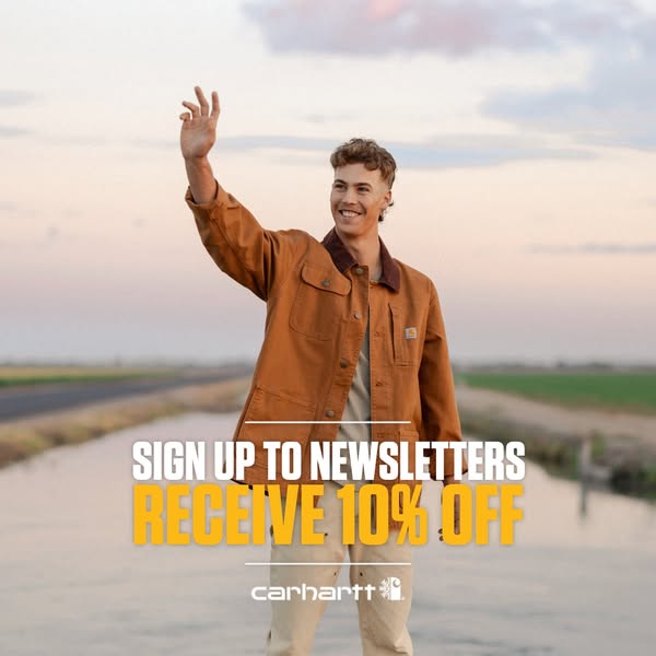 An image ad features a young man wearing a Carhartt jacket standing in a rural landscape with a sign-up offer for 10% of
