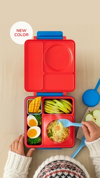 This image ad showcases a bento box that contains various food items inside of it. The bento box is red with blue accent