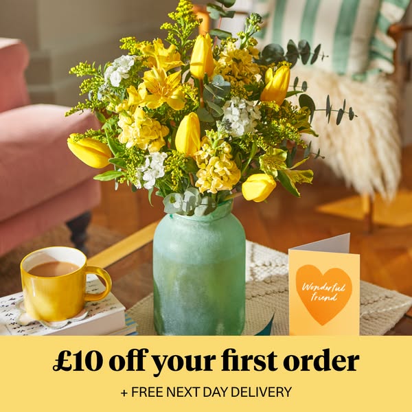 This image ad features a vibrant bouquet of yellow and white flowers in a green vase, accompanied by a greeting card. It
