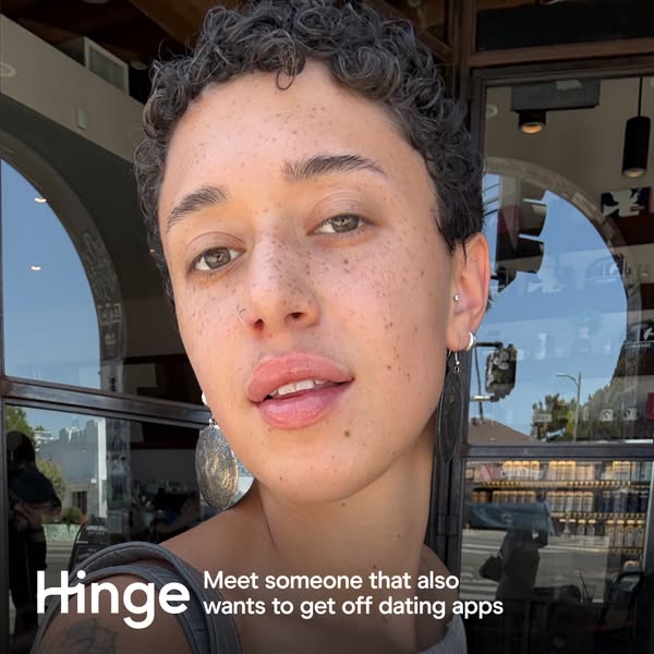This Hinge ad features a close-up selfie of a person with freckles and short curly hair. The ad's message is that Hi