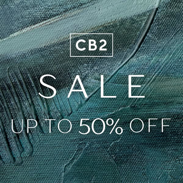 This static image ad promotes a sale by CB2, offering up to 50% off. The ad uses a close-up shot of a textured, painted 