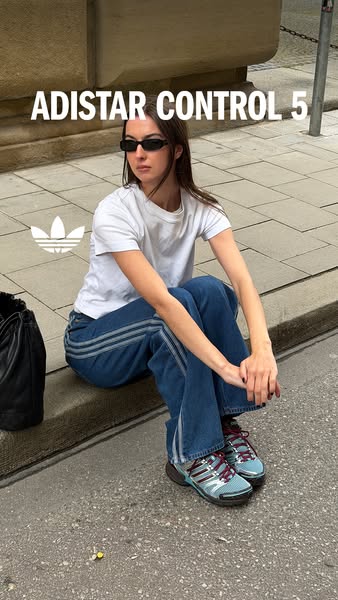 An Adidas image ad features a young woman wearing an Adistar Control 5 shoe while sitting on a street curb. The ad highl